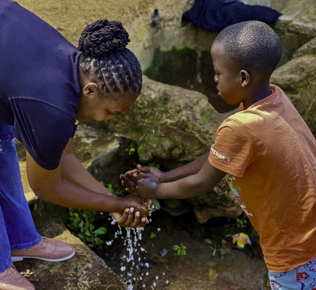 Woman with child and water washing hands in Kenya